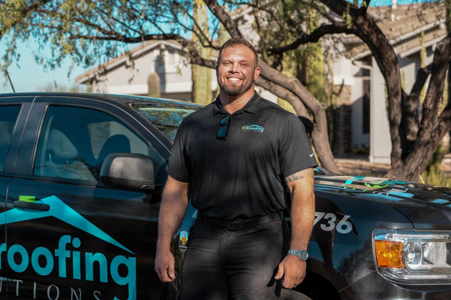 Eco Roofing Solutions team member in a branded polo beside a company pickup truck in a desert-landscaped Arizona neighborhood