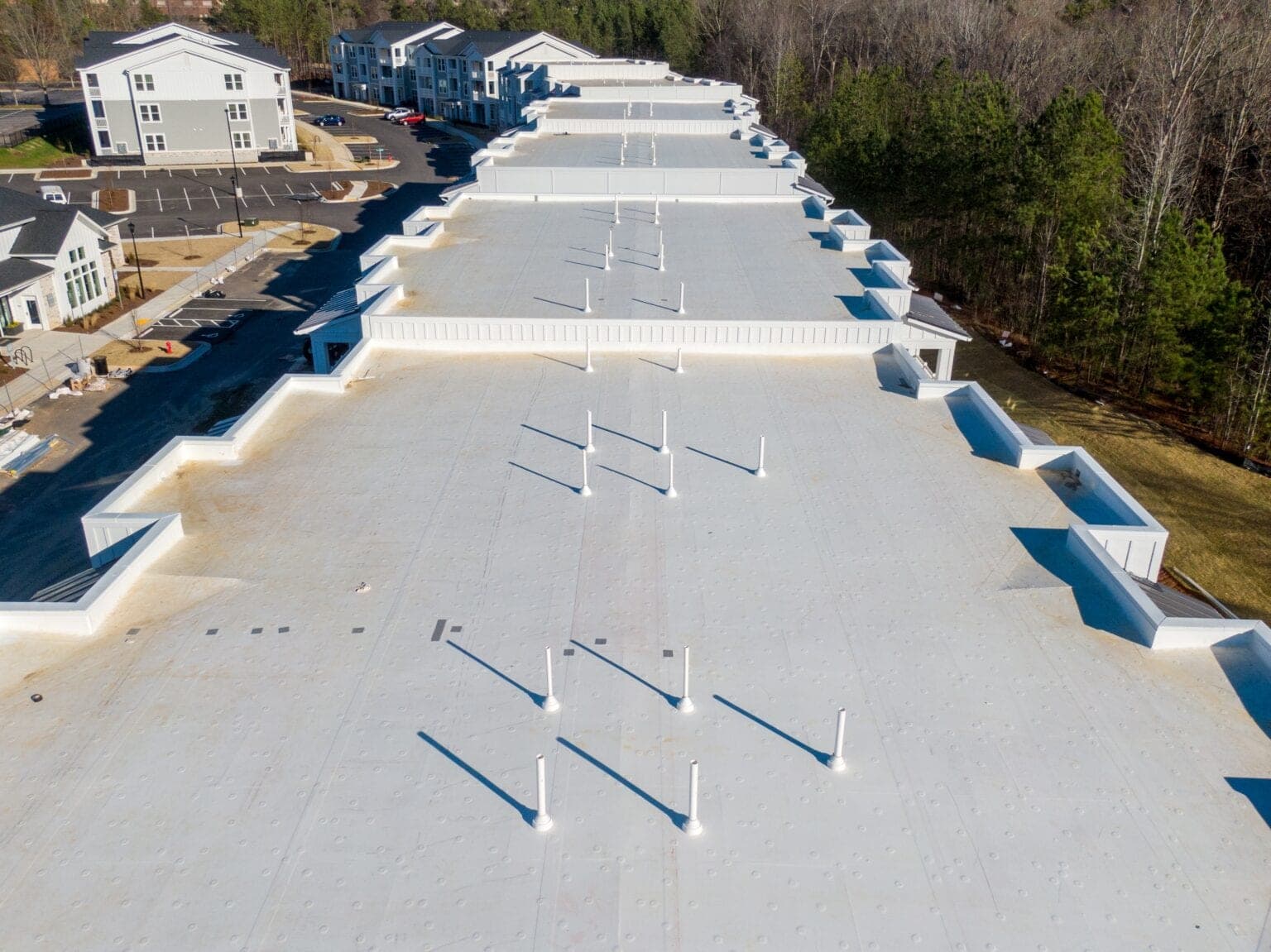 Drone view of a bright white single-ply TPO membrane covering an entire commercial building footprint