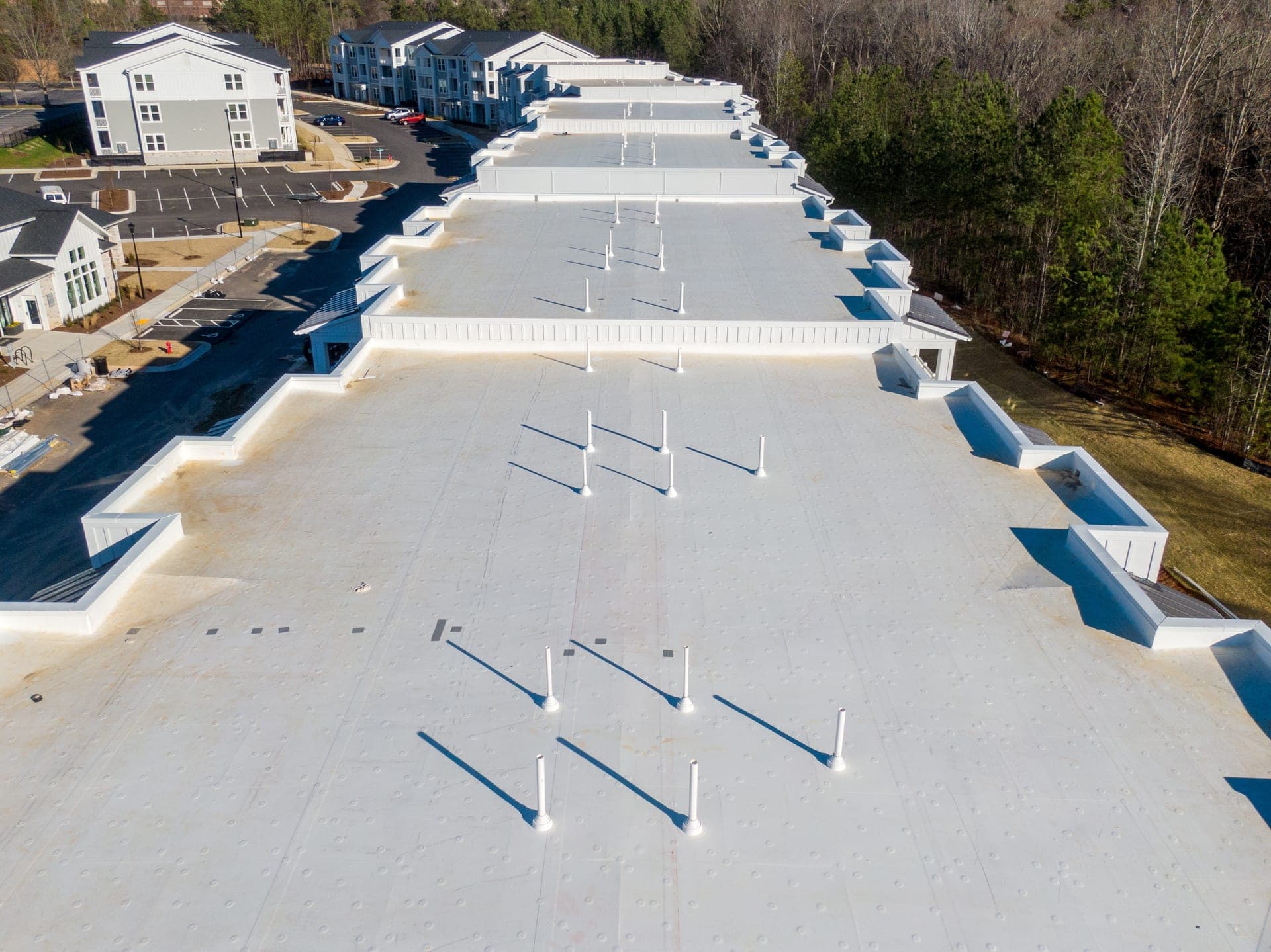 Aerial view of a bright white reflective roof system across a multi-building commercial property