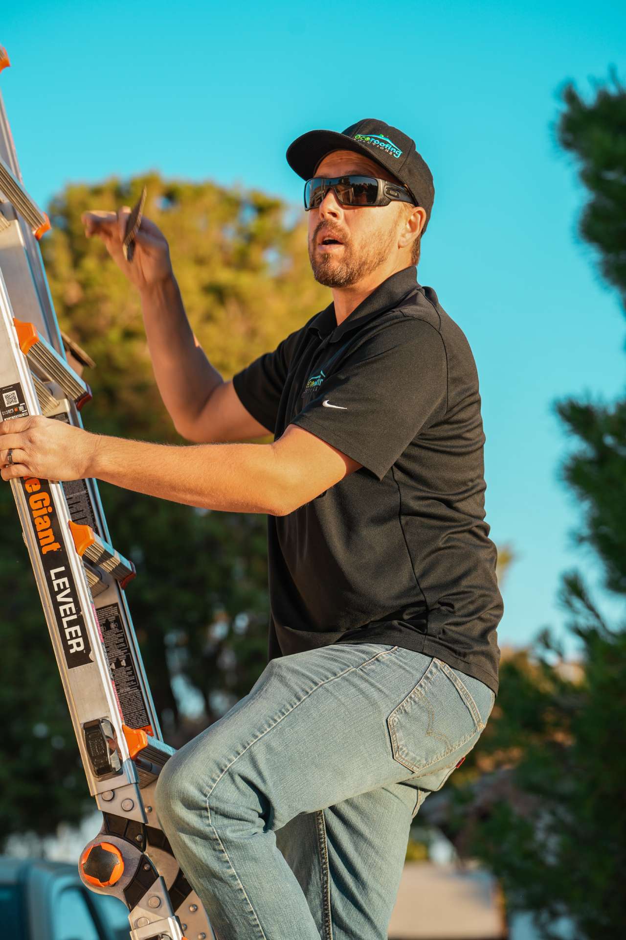 Eco Roofing Solutions roofer in a branded cap climbing an extension ladder to inspect a roof
