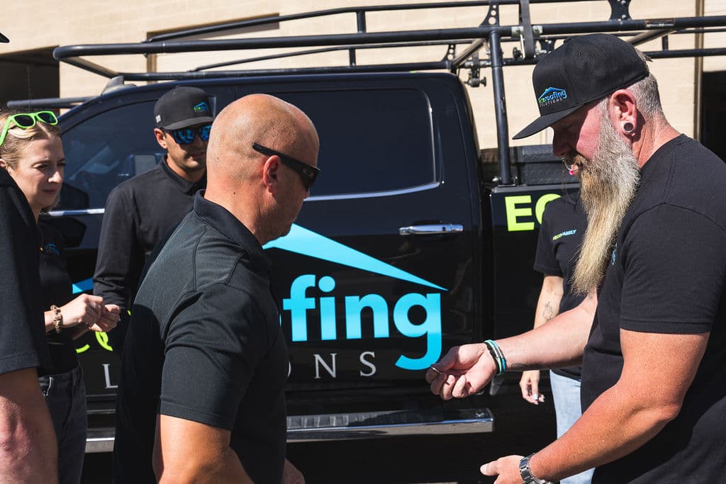 Eco Roofing Solutions crew members talking together beside a branded truck before heading out