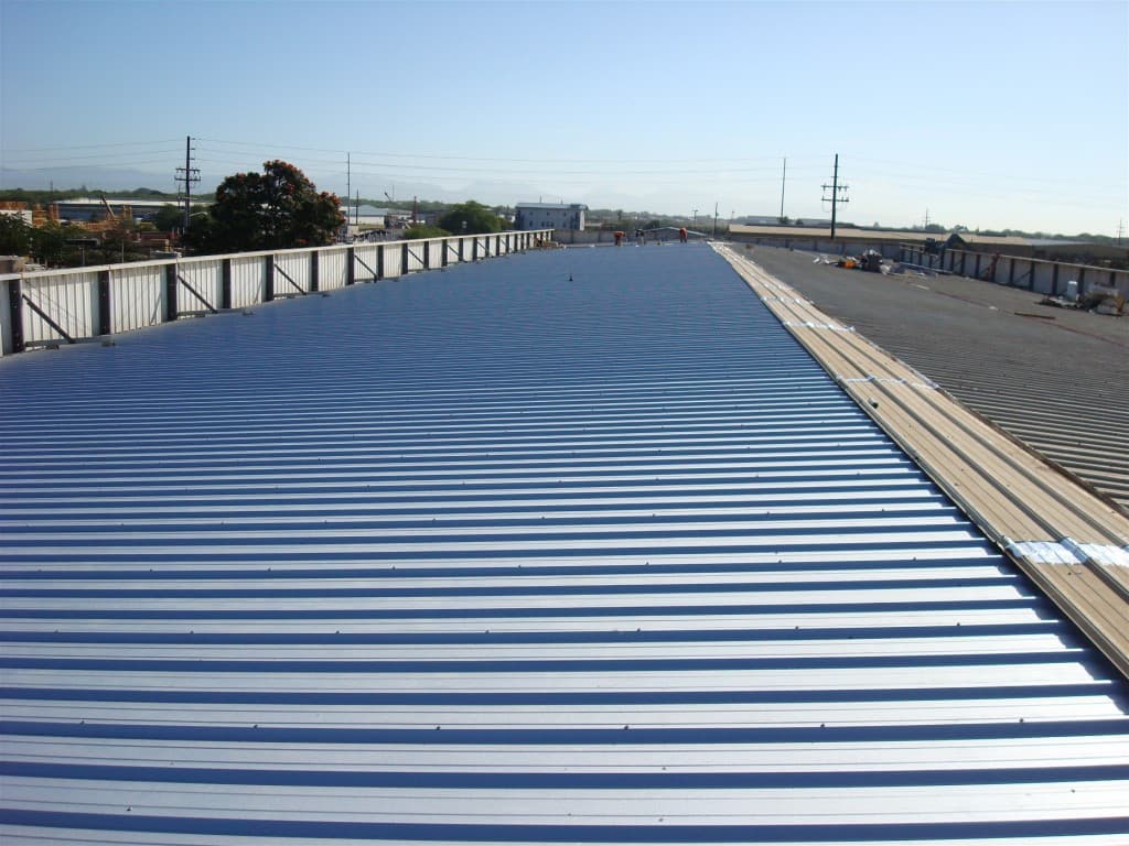 Long run of newly fastened standing seam metal roof panels stretching across a commercial building