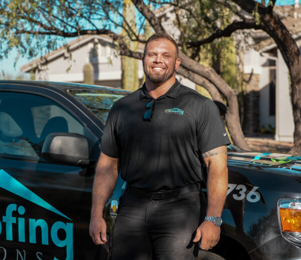 A smiling, bearded man in a black Eco Roofing polo shirt standing in front of a black company truck with "roofing solutions" branding.